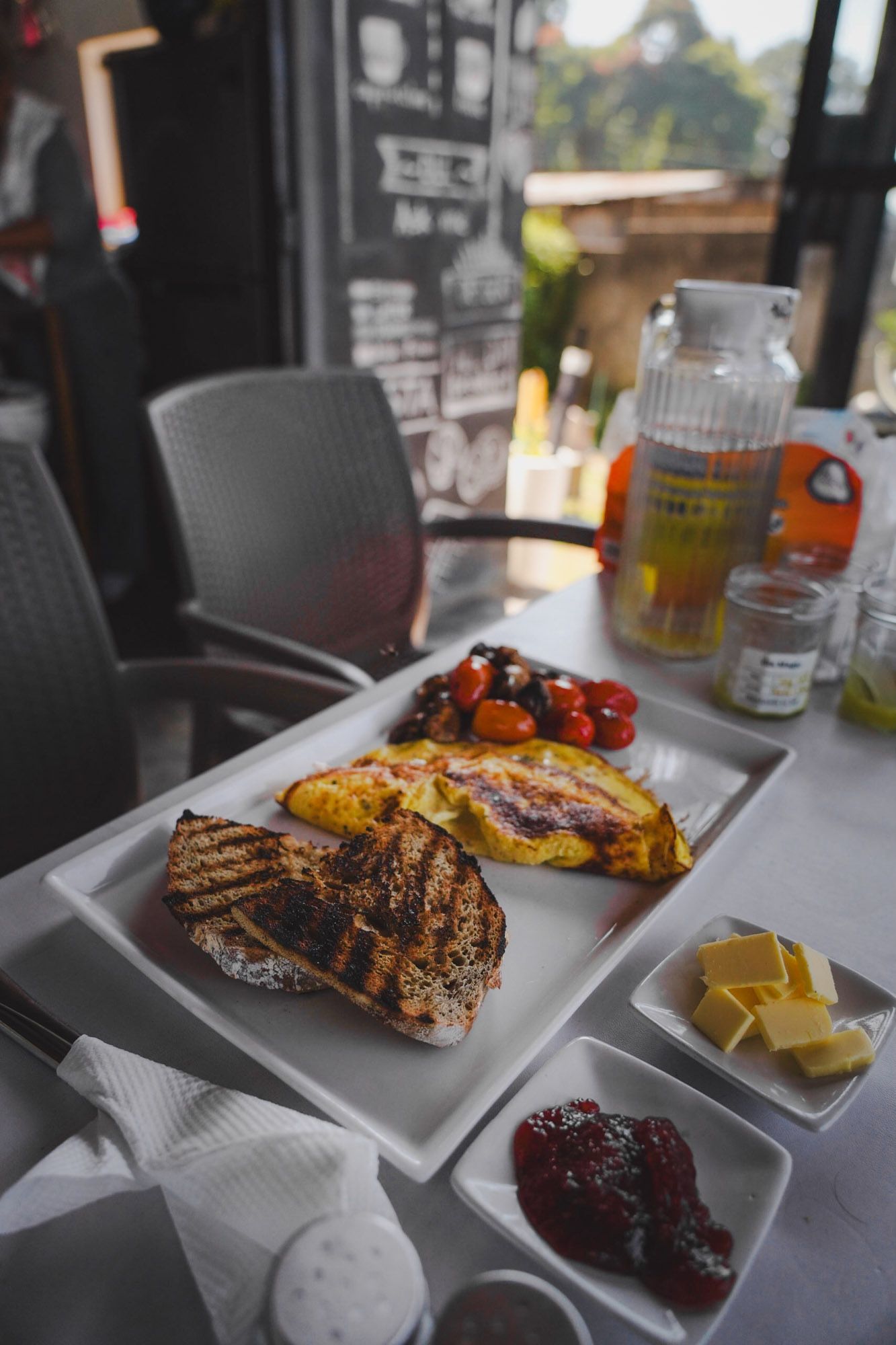 Bread, omelette, torched tomatoes, butter, jam — what arrives after twenty minutes.
